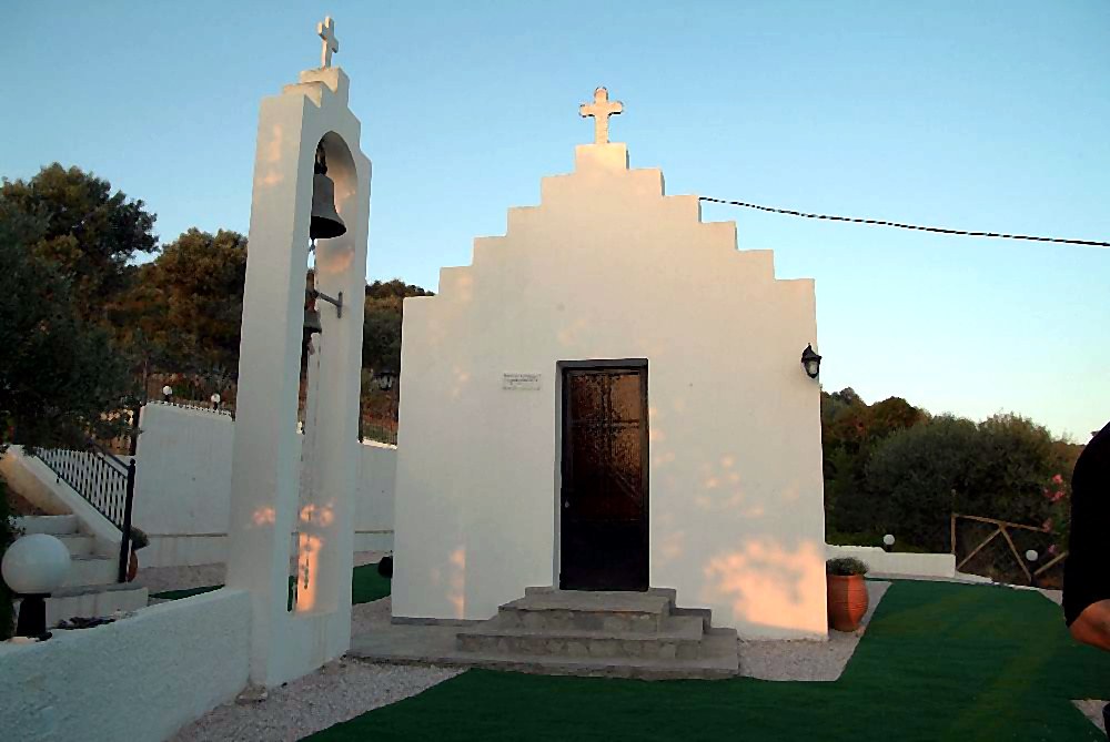 Το εκκλησάκι της Villa Domenica μέσα στο καταπράσινο περιβάλλον, με λευκά λουλούδια και πλακόστρωτο μονοπάτι