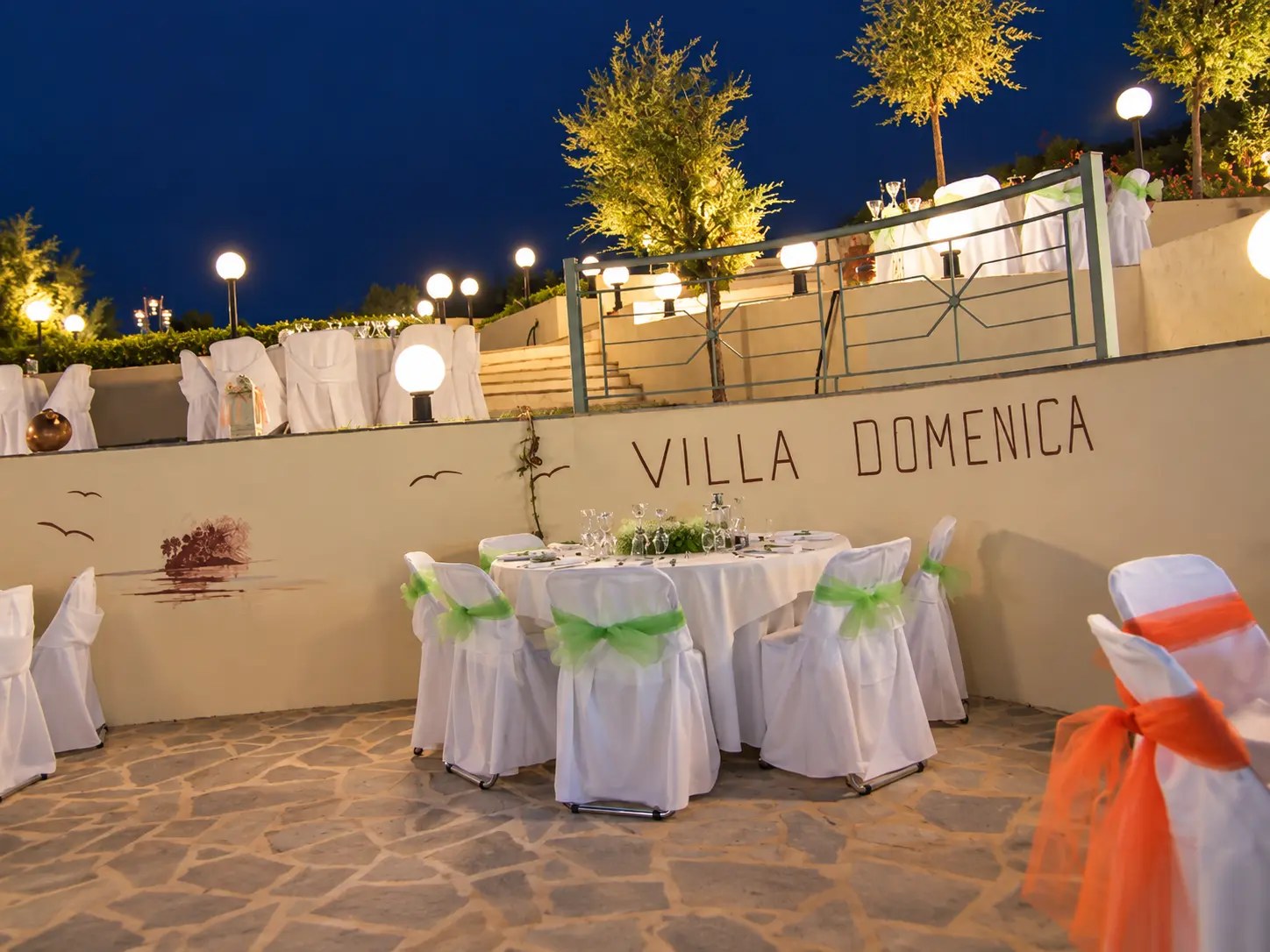 Η φωτισμένη πλακόστρωτη αυλή του Villa Domenica το βράδυ